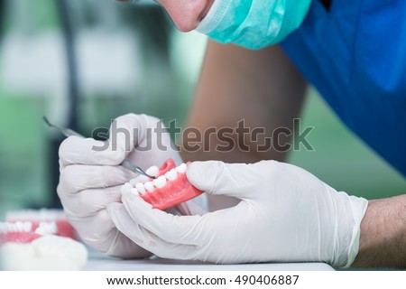 Dental prosthesis, dentures, prosthetics work. Prosthetics hands while working on the denture, false teeth, a study and a table with dental tools. Royalty-Free Stock Photo #490406887