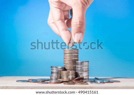 Male hand putting coin money like stack growing business on blue background. Finance and Money concept, Hope of investor concept