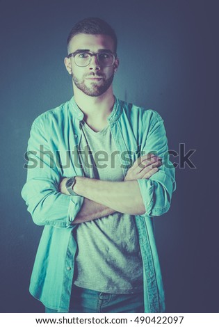 Portrait of a happy casual man standing isolated on a dark background
