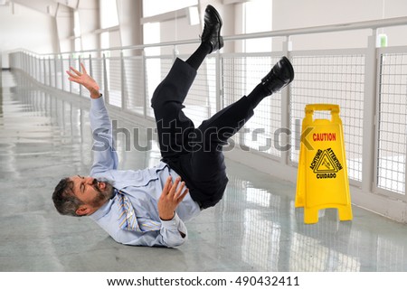 Hispanic businessman falling on wet floor inside office building