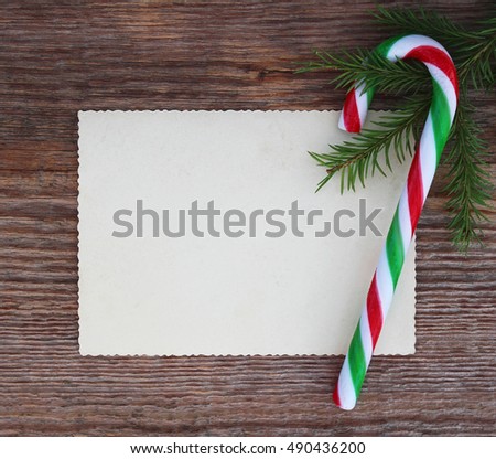 Christmas card: empty paper form and candy cane with fir-tree branches on old wooden background