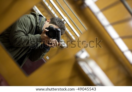 young man on a train taking a self portrait with the able assistance of a mirror