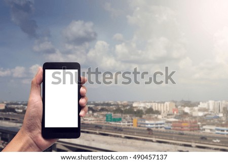 hand holding smartphone with blank screen for text on cityscape background.