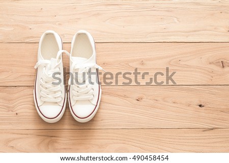A pair of white canvas shoes on a wooden Royalty-Free Stock Photo #490458454
