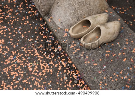 A pair of typical wooden shoes from a carnival participant in front of a house entrance with orange confetti on the ground. Basel carnival 2015
