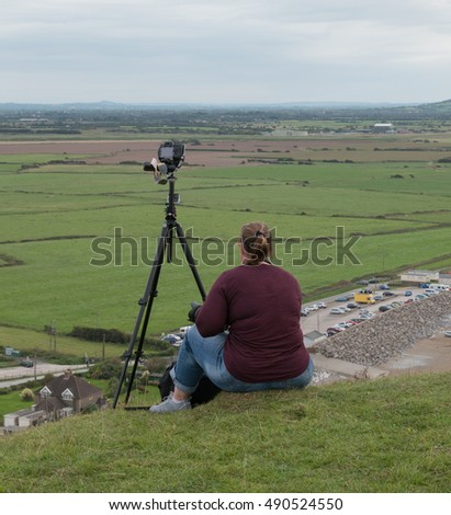 Female Photographer with a Camera on a Tripod on Top of Brean Down, a Limestone Promontory in the Bristol Channel and part of the Mendip Hills in Somerset, England, UK
