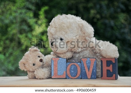 Two white teddy bears with Love stones against green nature background 