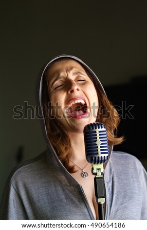 Young girl emotionally singing in a microphone