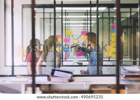 Groupe of casual business people working in front of glass wall using notes papers post it. Seen through glass in Startup office. Royalty-Free Stock Photo #490695235