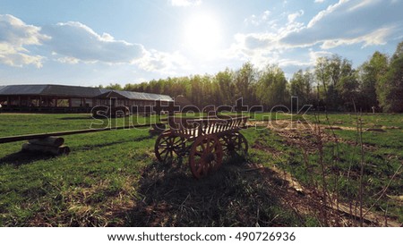 Smooth steady camera slide shot around Russian wooden cart in a field, clean blue sky with sun shining.