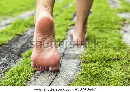 woman's feet walking on the grass. old wood Royalty-Free Stock Photo #490740649