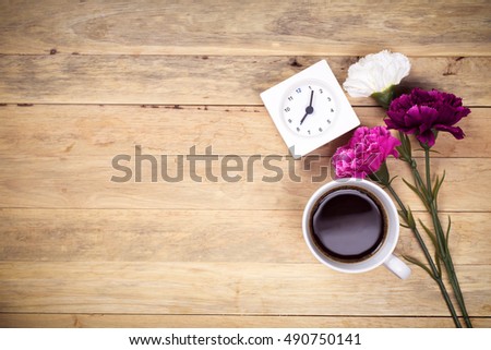 cup of coffee, bouquet of carnation and clock on wooden background

