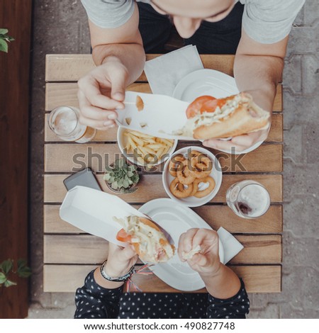 A Couple Eating Hotdogs Outdoors
