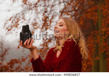 Pretty smiling woman in fall forest park taking selfie self photo with old vintage camera. Happy gorgeous young girl passionate photographer. Autumn winter photography.