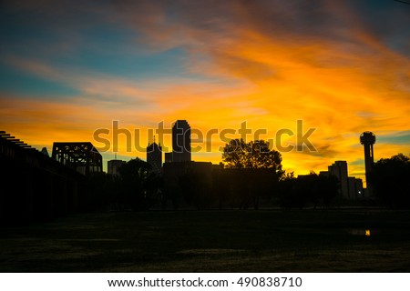 Dallas Texas right before sunrise with silhouette of downtown skyline cityscape with Reunion Tower and highest skyscraper with railroad track bridge in the night