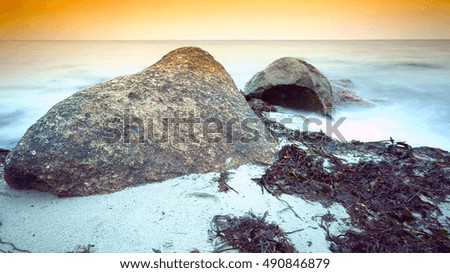 sunset beach with waves and stones,shells,seaweed and orange background
