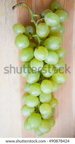 a large bunch of green grapes on a wooden board
