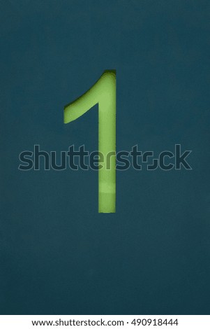 Green lettering number 1 on a petrol colored Sign with white striped house wall