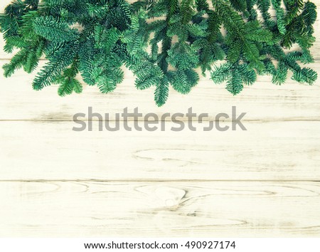 Christmas tree branches over bright wooden background. Vintage style toned picture