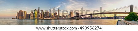 Skyline of Manhattan during sunrise on a beautiful summer morning. Includes Statue of Liberty. Panorama.