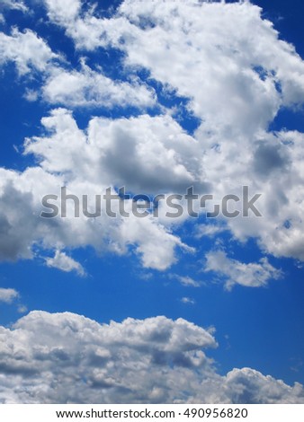Vertical background image of thick, puffy, multi-layered white clouds on a vibrant blue sky.