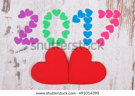 Happy new year 2017 made of colorful paper hearts and red wooden hearts on old wooden rustic background