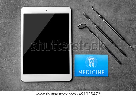 Medical service concept. Visiting card, dental equipment and tablet on grey background