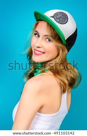 Cheerful smiling young woman in casual t-shirt and baseball cap. Beauty, youth  style. Healthy white teeth. Studio shot. 