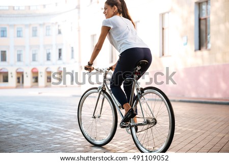 Young brunette woman riding on bicycle in city street