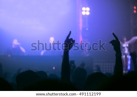 Dj Picture of rock concert, music festival, New Year eve celebration, party in nightclub, dance floor many people standing with raised hands up and clapping, happiness and night life concept