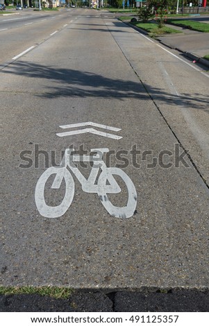White bicycle sign on asphalt bike lane on city street. Concept background for Air Pollution Reduce and Cycling Health Benefits.
