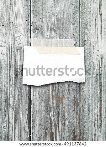 Close-up of one blank ripped pieces of paper with adhesive tape on gray wooden background