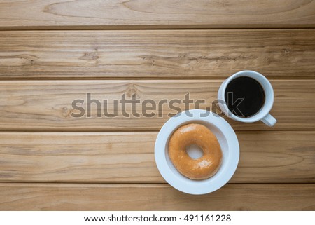 Dessert and drink image of donut or doughnut and hot coffee on vintage wooden table , top view background