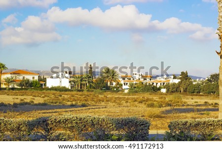 Landscape of town Paphos with houses, trees and mountains in background against blue sky, Cyprus. Photos warm colors of setting sun