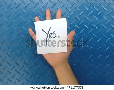 Hand Holding Paper with Yes Letter on blue Background Texture