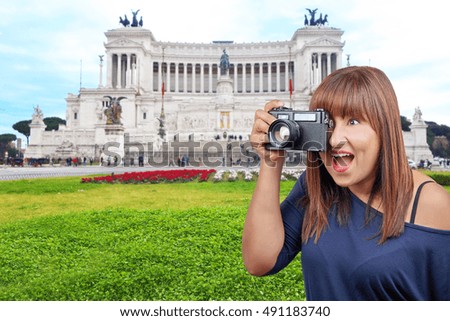 Beautiful brunette woman taking photo with vintage reflex at Monument to Victor Emanuel II Rome, Italy