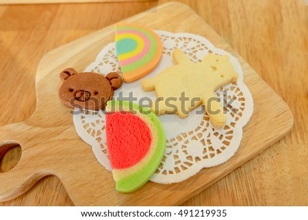 Homemade cookie in the shape of bear, rainbow and watermelon on the wooden table. 