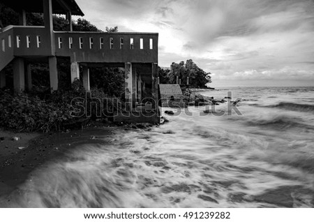 black and white image wave hitting the coastline with dramatic cloud background