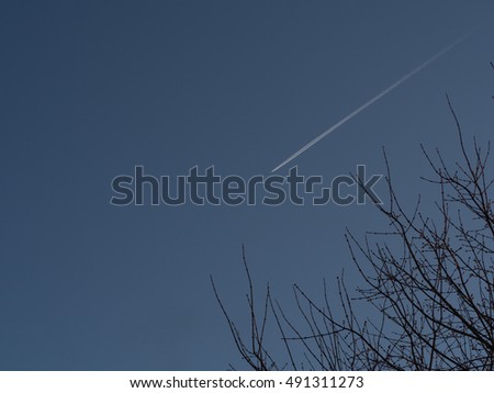 trace of the plane silhouetted against a blue sky with clouds