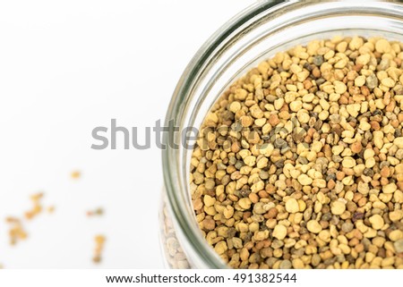 Closeup of bee pollen.Bee pollen granules in glass jar/container.bee pollen boosts the immune system.Food ingredient for health,healthy leaving, medical,health-care concept. Isolated,white background.