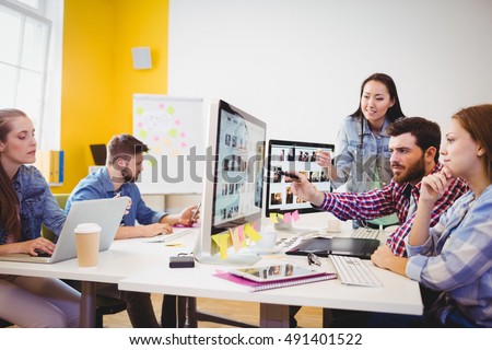 Businessman showing computer screen to coworkers in creative office Royalty-Free Stock Photo #491401522