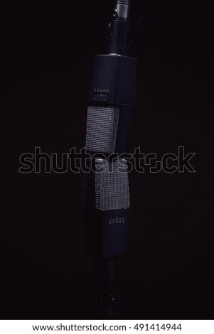 Two microphones for recording stereo sound, on stands in dark ambiance. 