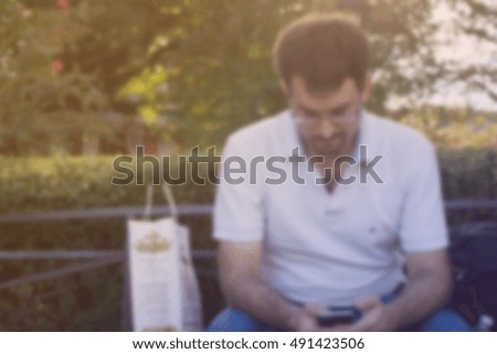 blurred man using and touching smart phone at park, filtered color tone
