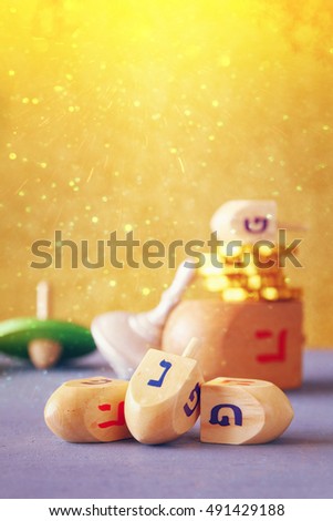 Image of jewish holiday Hanukkah with wooden dreidels colection (spinning top) and chocolate coins on the table. Glitter overlay