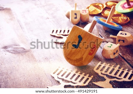 Image of jewish holiday Hanukkah with wooden dreidels colection (spinning top) and chocolate coins on the table. Glitter overlay