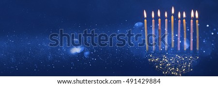 Low key Image of jewish holiday Hanukkah background with menorah (traditional candelabra) and burning candles. Glitter overlay. Wide format