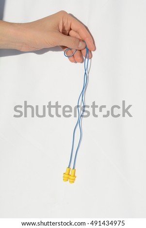 holding a pair of earplugs on a white background. ear plugs for hearing protection