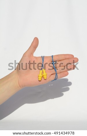 holding a pair of earplugs on a white background. ear plugs for hearing protection