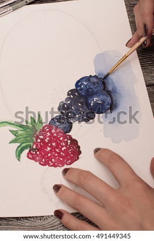 artist woman painter drawing a watercolor berries on white paper. closeup