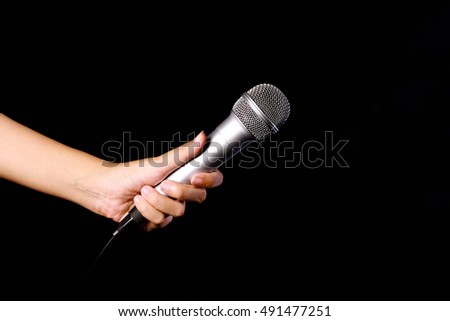 a hand holding microphone isolated on black background